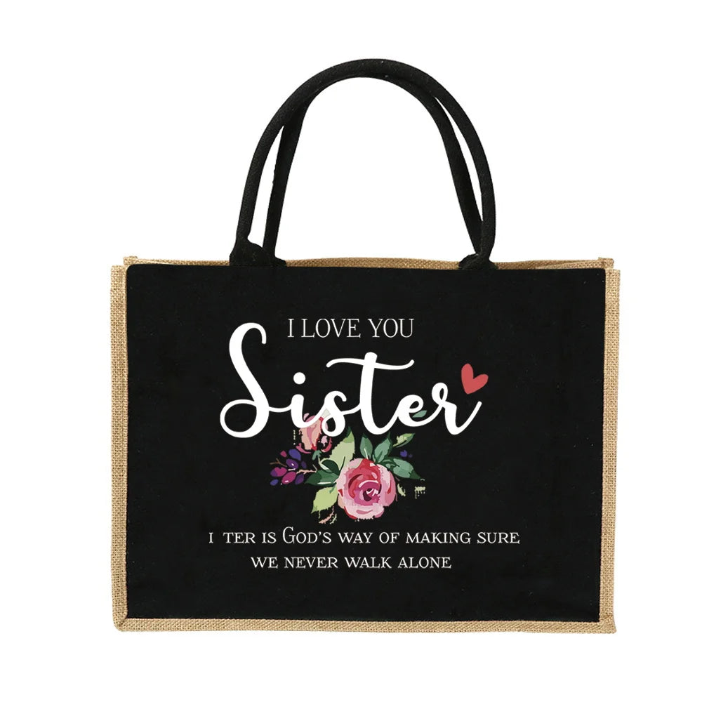 Schwarze Jute-Tasche mit weißem gesticktem Text „I love you sister“ und rosa Blumenmuster