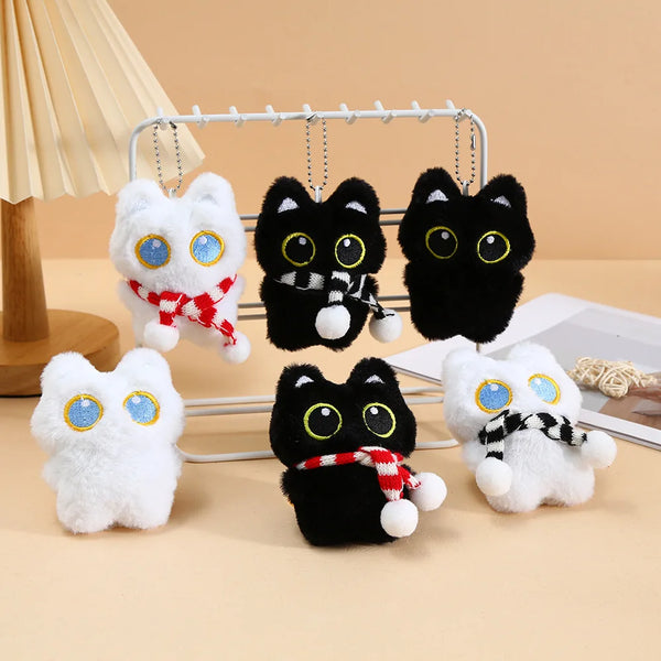 Collection de charmets de clés en peluche de chats noirs mignons avec fourrure blanche et accents rouges, exposés sur un prés