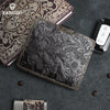 A black genuine leather card wallet with gold stitching is displayed on a dark gray surface next to an open notebook.
