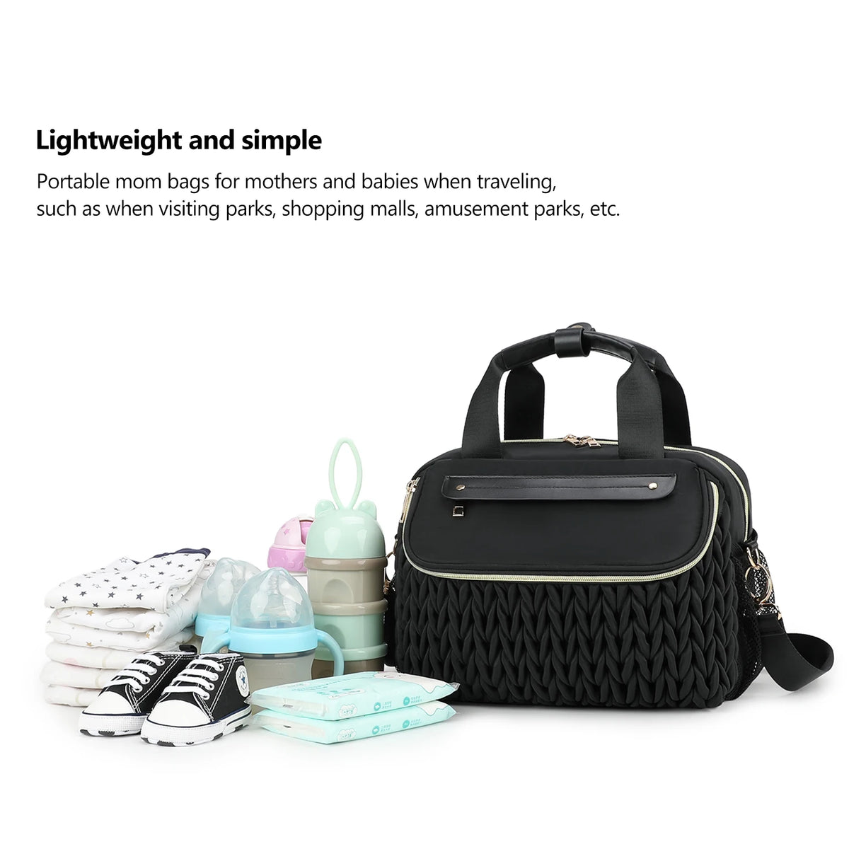 A black quilted mommy bag with a strap is shown next to various baby items like diapers and shoes.