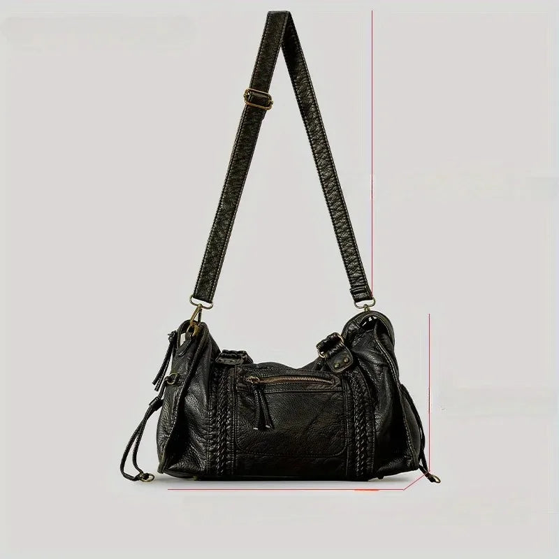 A black vintage washed leather tote bag with a long strap is shown against a light gray background.