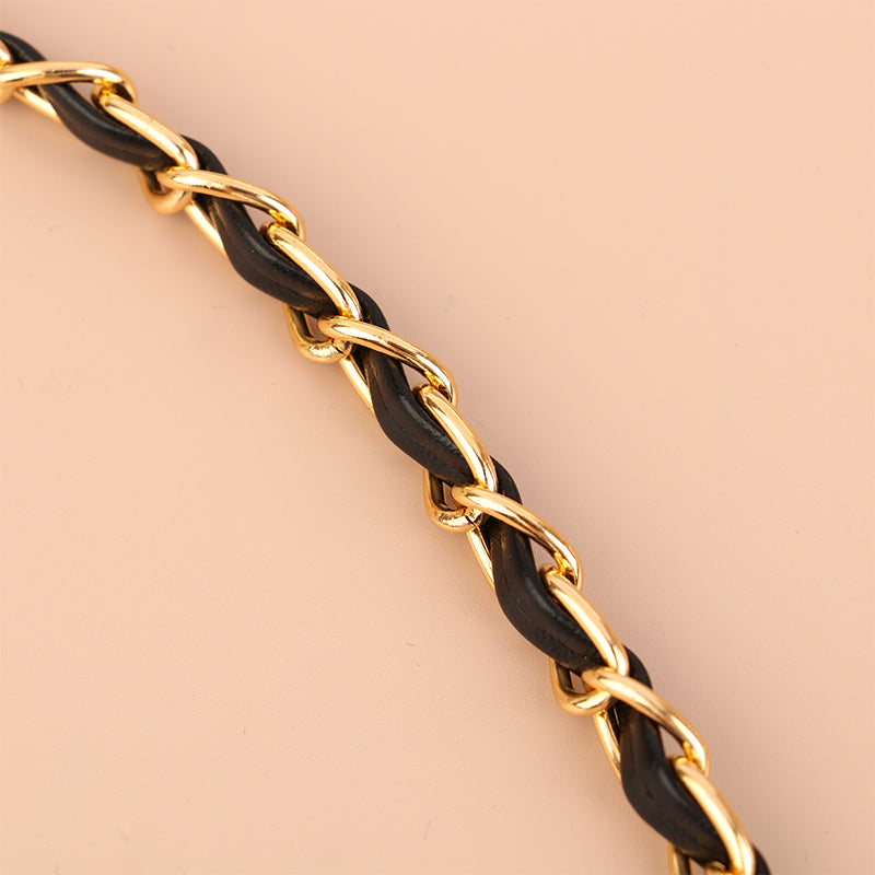 A close-up of a gold and black leather chain strap for an adjustable crossbody purse.