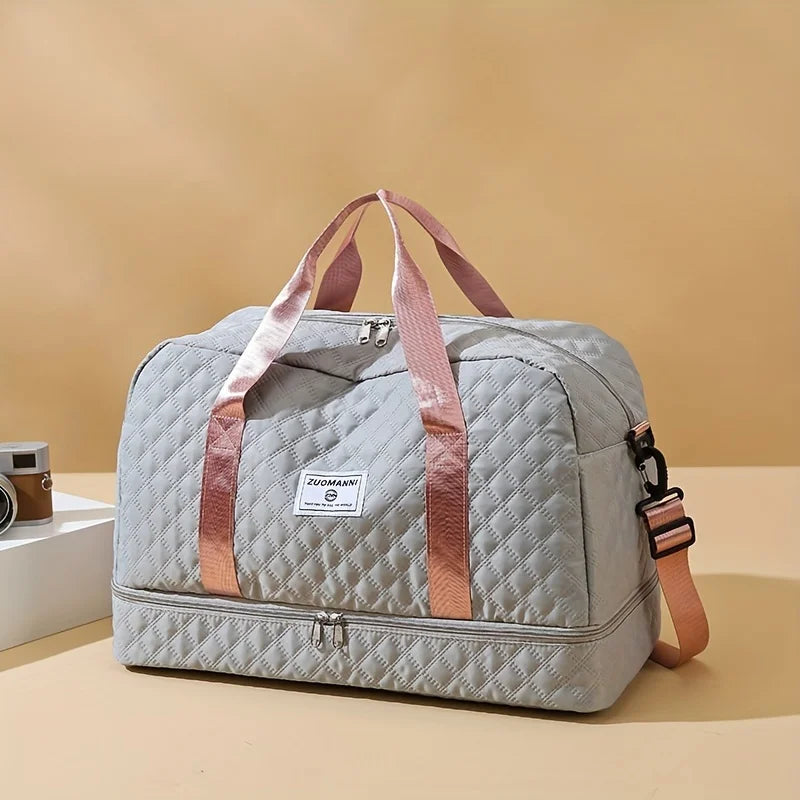 A light gray durable nylon travel duffle bag with pink straps resting on a beige surface.