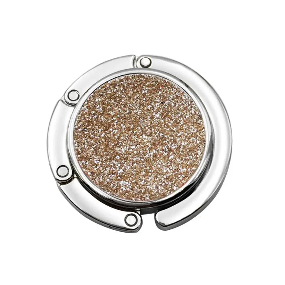 A close-up of a silver metal desk hook with a round, glittery brown coating.