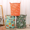 Trois paniers à linge en tissu aux motifs orange, sarcelle et vert debout.