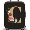 A black suitcase with a gold initial C design and floral accents, sitting on rolling wheels.