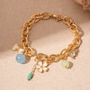 Gold chain bracelet featuring ocean pearl charms including a starfish, shell, and flower accents.