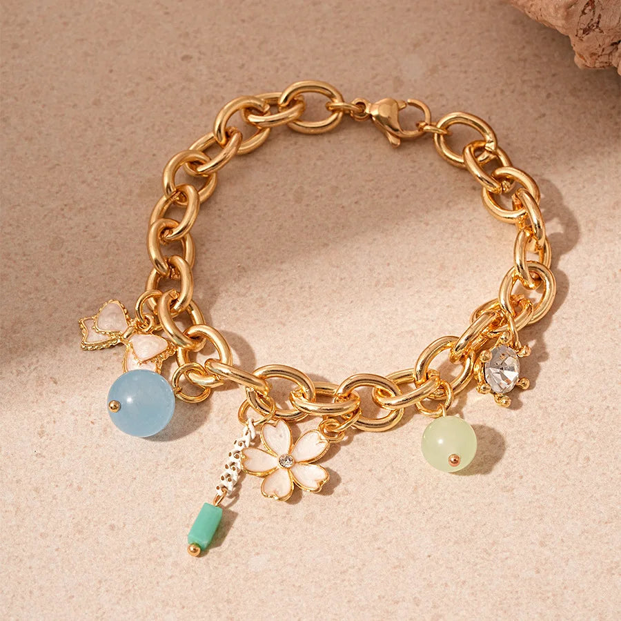 Gold chain bracelet featuring ocean pearl charms including a starfish, shell, and flower accents.