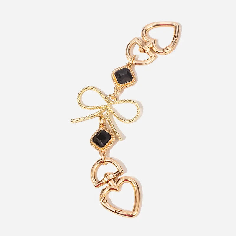 Gold metal purse chain strap with decorative charms and a heart pendant
