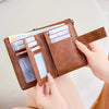 A brown leather multi-slot wallet with multiple cards is held by a person.