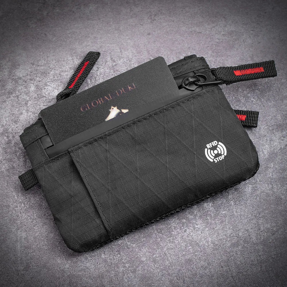Black RFID blocking travel wallet with a carabiner clip resting on a gray background.