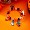 A bracelet made of amber and black beads featuring Halloween pumpkin and ghost charms.