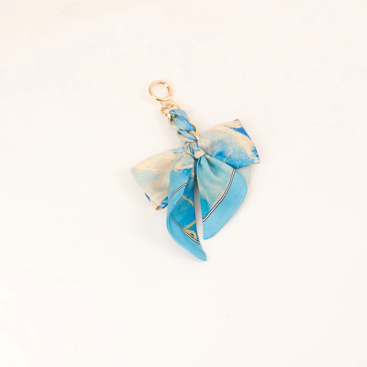 Lazo de cinta de seda azul claro atado en un nudo, unido a un anillo de llavero dorado.
