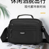 A black AOTIAN compact waterproof crossbody messenger bag resting on an open book.