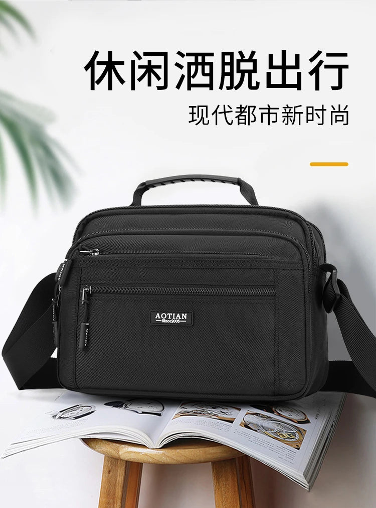 A black AOTIAN compact waterproof crossbody messenger bag resting on an open book.