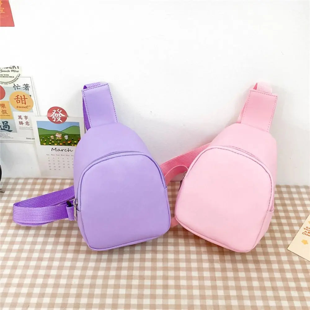 A pair of purple and pink nylon crossbody bags for kids displayed on a checkered surface.