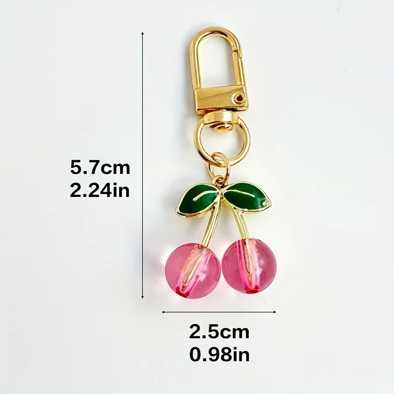 Gold-toned keychain featuring green leaves and pink fruit charms.