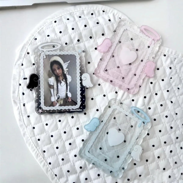 A white quilted surface holds three clear acrylic photo card holders with pink, purple, and blue accents.