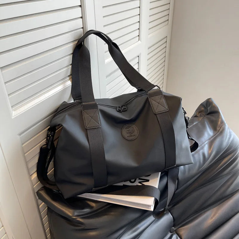 A black Versatile Oxford Cloth Travel Tote Bag hanging in front of a white slatted door.