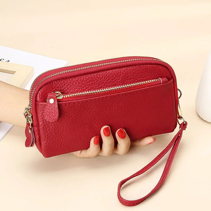 A red genuine cowhide leather double-zip wristlet wallet is shown being held by a hand.