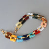 A bracelet made of multi-colored acrylic chain links in shades of red, green, yellow, and white.