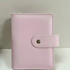 A pink leather ring binder notebook with a stitched closure.