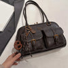 A dark brown leather vintage letter print crossbody bag with brass hardware being held by a hand.