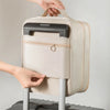 A hand is holding a beige portable luggage shoe organizer bag with a black handle and zipper.