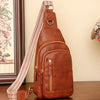 A brown PU leather crossbody sling bag with a patterned strap resting on a wooden surface.