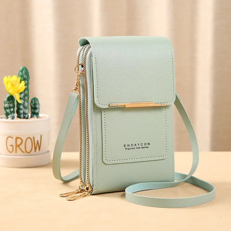 A mint green luxury women's crossbody shoulder bag with gold hardware resting on a light wooden surface.