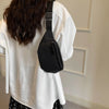 A person wearing a white shirt holds a black nylon crossbody sling bag.