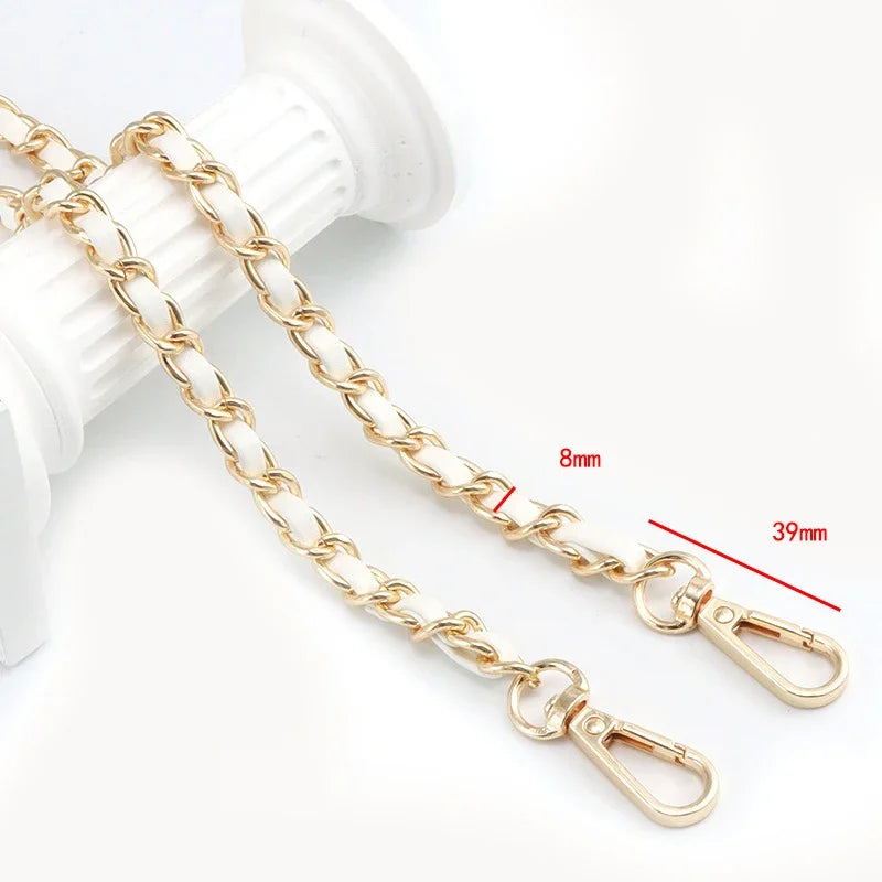 Gold-colored metal chain shoulder strap for crossbody bags shown next to a white object.