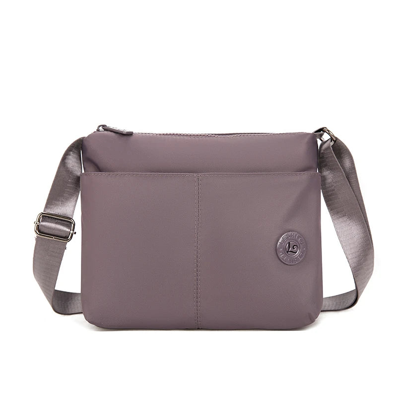 A mauve waterproof nylon crossbody bag with a flap and strap is shown against a white background.
