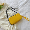 A bright yellow multi-functional passport and document organizer bag with black strap lying on white fabric.