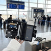 A black polka dot passport holder with multiple card slots is held in a person's hand in an airport setting.