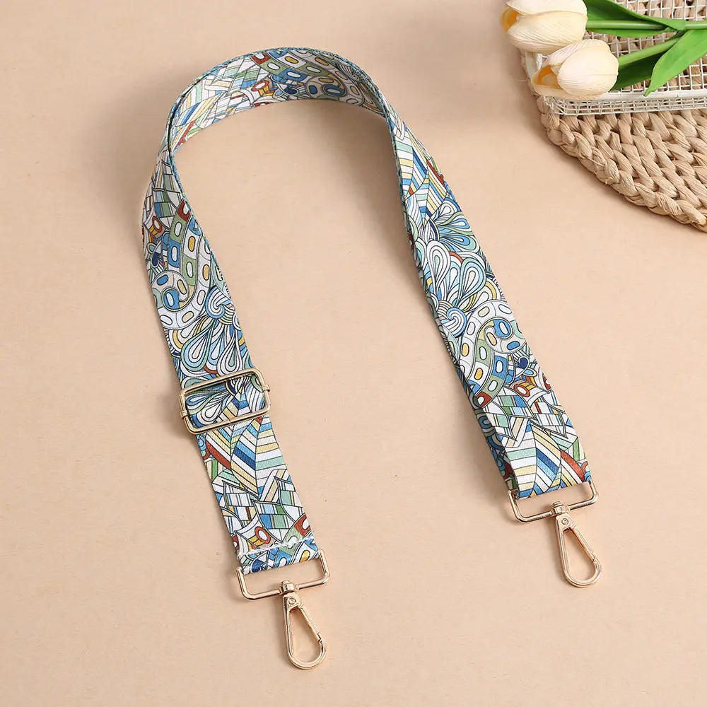 A beige adjustable bohemian printed crossbody strap with blue and white patterns is displayed on a light background.