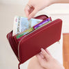 A hand is opening a maroon PU leather zipper wallet to show various credit cards and cash inside.