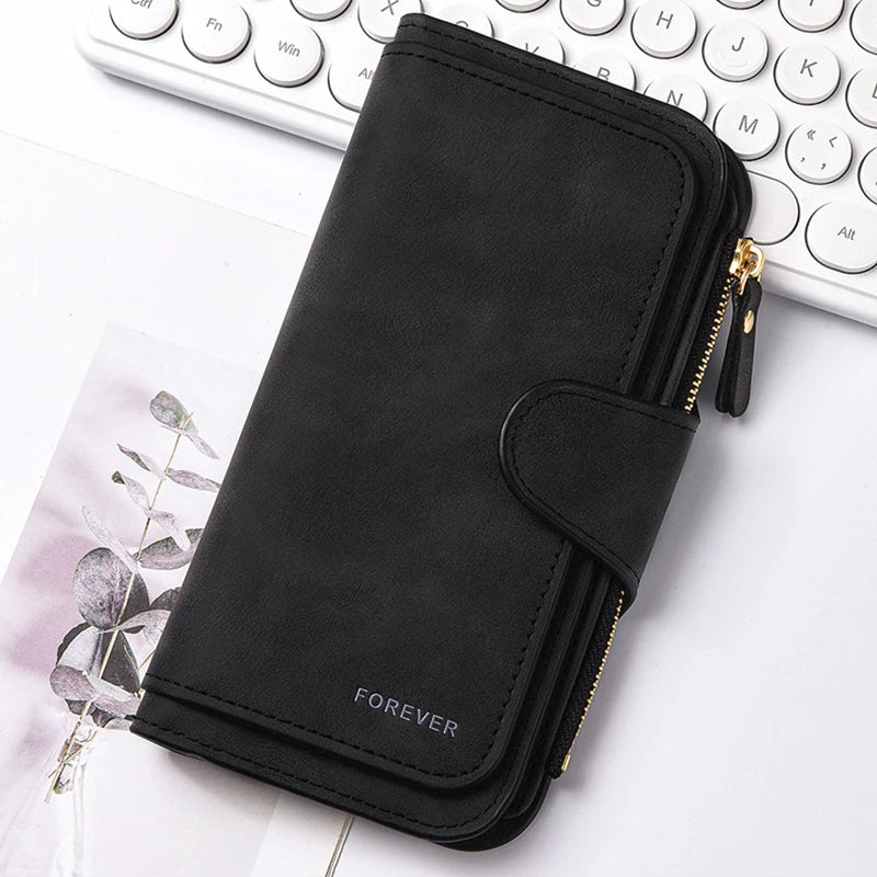 Cartera de cuero sintético negro con cierre de cremallera sobre una superficie blanca junto a un teclado de portátil