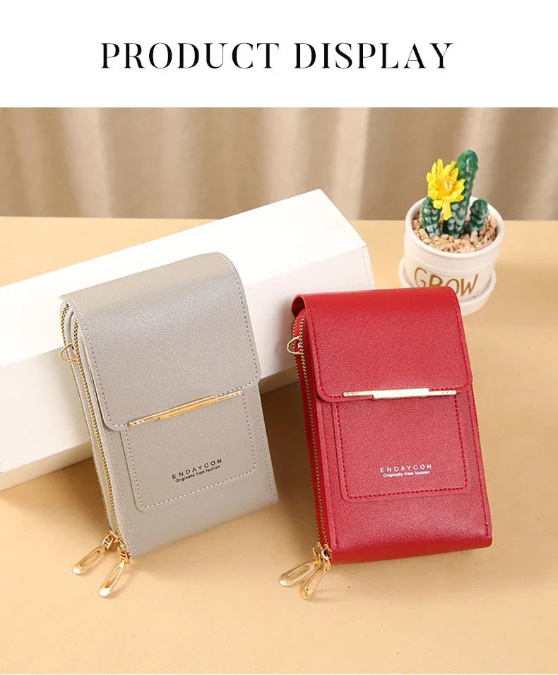 A display of a light gray and red luxury women's crossbody shoulder bag next to a small potted succulent plant.