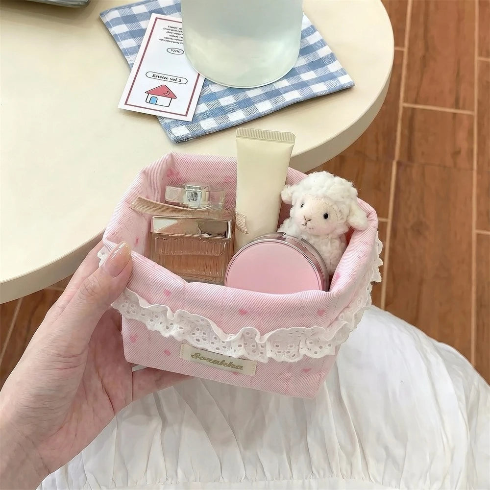 Light pink fabric storage basket with a heart and bow holding skincare products and a small white stuffed animal