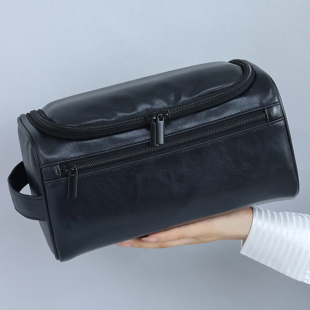 Schwarze Vintage-PU-Leder-Toiletten-Tasche mit Reißverschluss und Aufhänger, in der Hand gehalten.