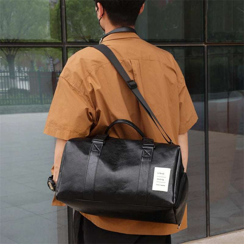 A man wearing a brown shirt carries a black leather travel duffle bag over his shoulder.