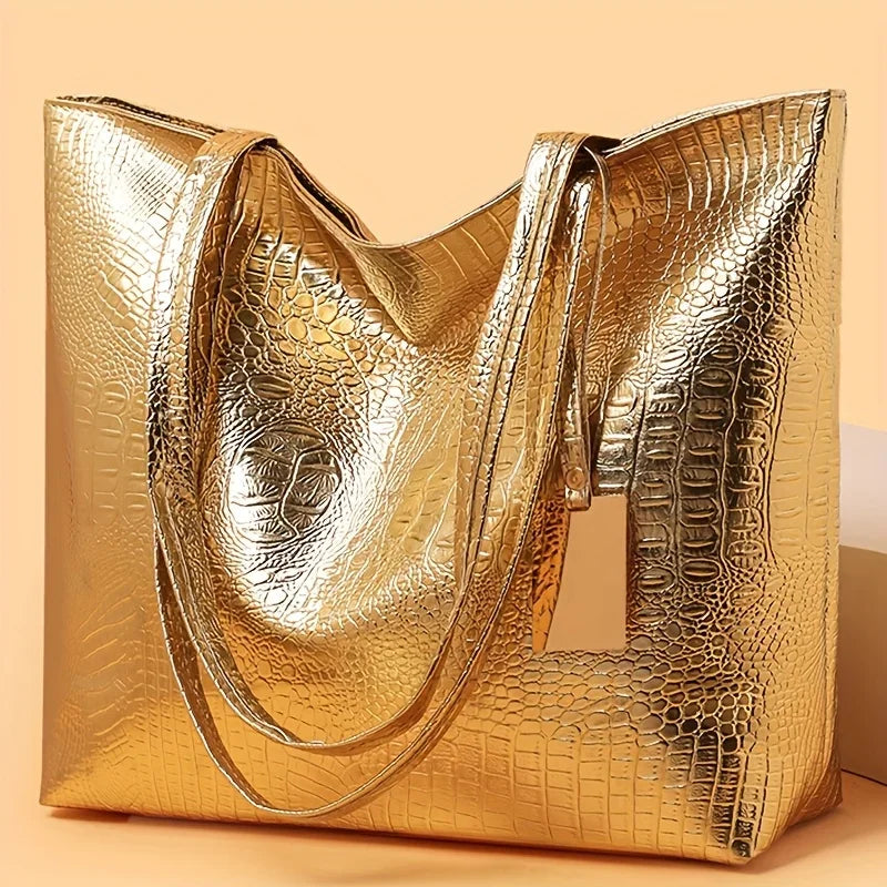 A golden metallic crocodile print zipper tote bag shown in a studio setting.