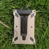 A slim aluminum metal ID card wallet with a matte beige finish and black accents resting on green grass.