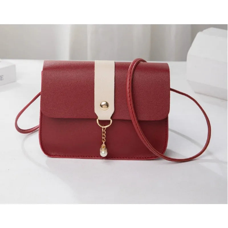 A maroon fashion square crossbody bag with a light beige strap and gold chain detail.
