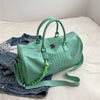 A mint green crocodile grain PU leather travel duffle bag resting on a white surface.