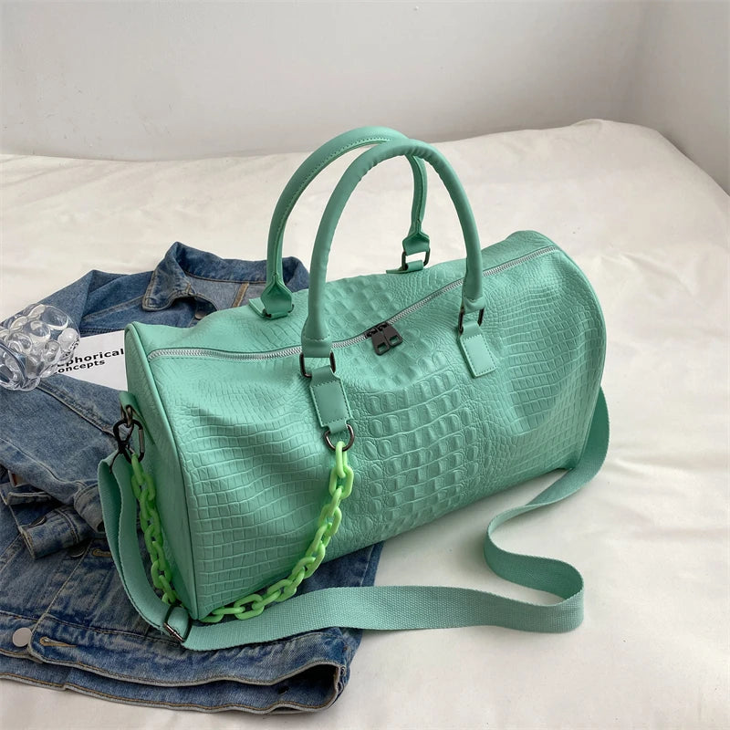 A mint green crocodile grain PU leather travel duffle bag resting on a white surface.