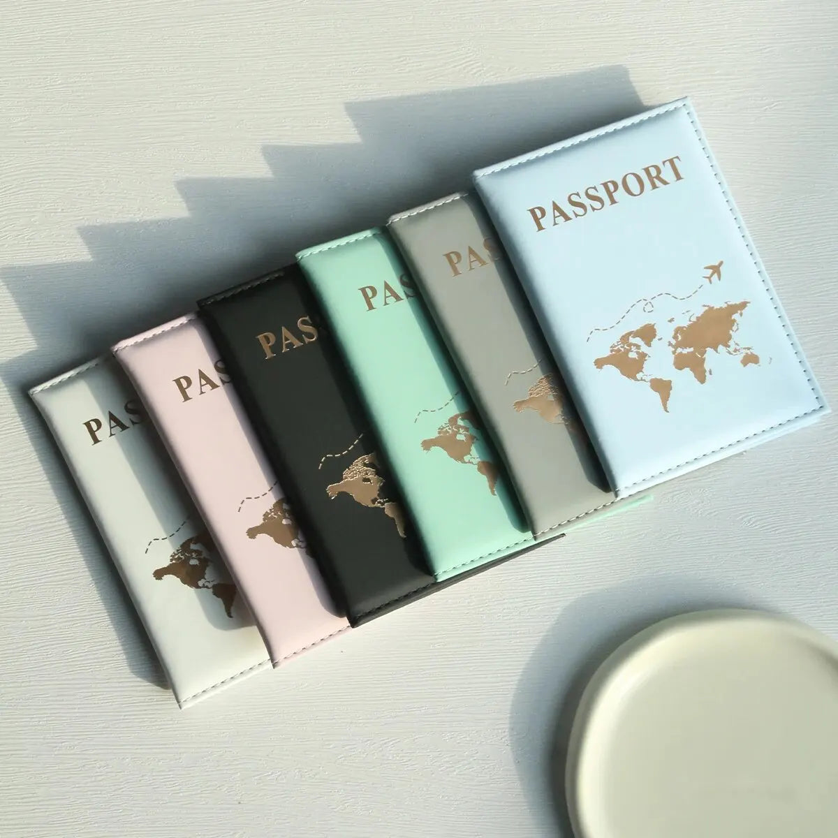 Sammlung von Leder-Reisepass- und ID-Halterern in verschiedenen Pastellfarben, arrangiert mit Weltkarten-Design.