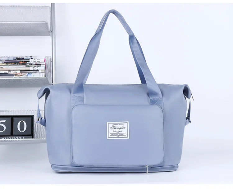 A light blue expandable travel organizer bag with handles is shown next to a shelf.
