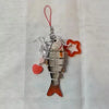 A silver simulation fish keychain with an orange heart charm and a red string.